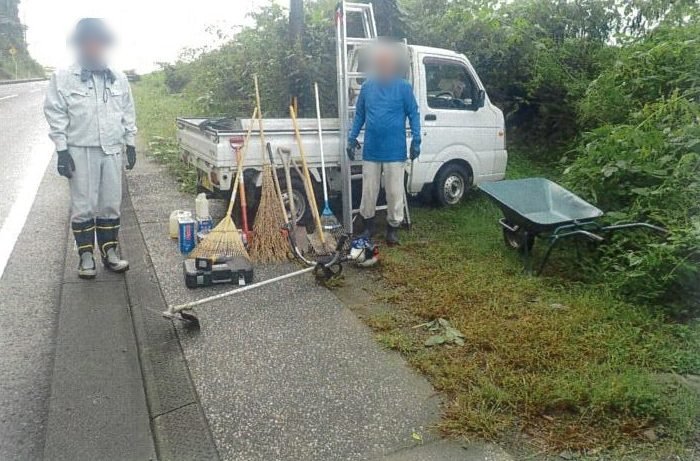 道路脇に止めた軽トラックと清掃道具